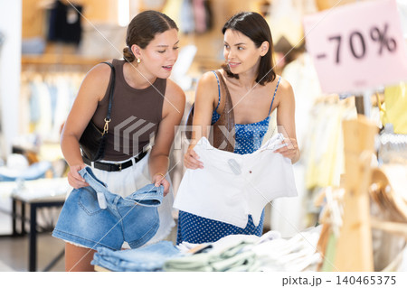 Two girls customer chooses shorts in store Two girls customer chooses shorts in store 140465375