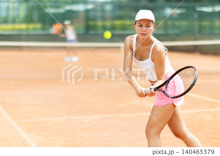 Female athlete plays tennis on open court Female athlete plays tennis on open court 140465379