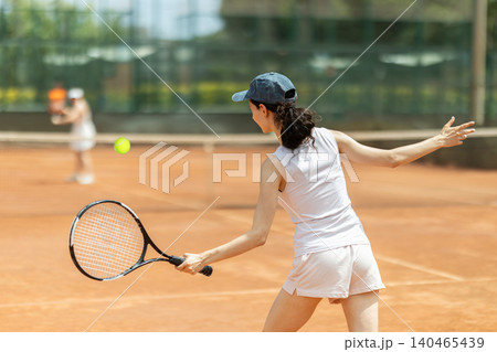 Concentrated sporty girl with tennis racquet and ball in her hands standing and ready to play match standing 140465439