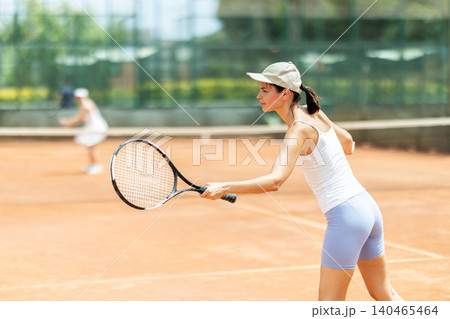Concentrated sporty girl with tennis racquet and ball in her hands standing and ready to play match standing 140465464