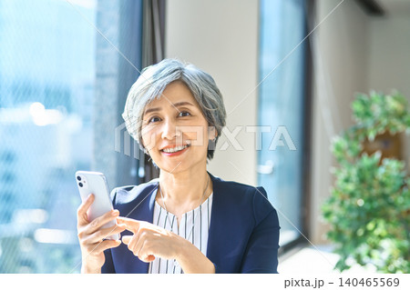 窓辺でスマホを操作する女性 140465569