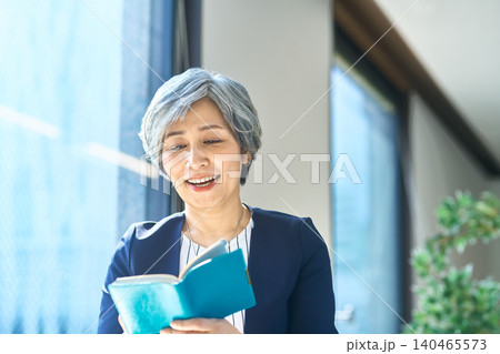 手帳を見て笑顔になる女性 手帳を見て笑顔になる女性 140465573