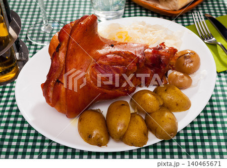 Appetizing pork knuckle and sauerkraut served with potatoes and onion Appetizing pork knuckle and sauerkraut served with potatoes and onion 140465671