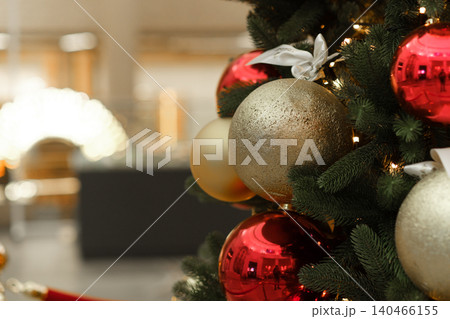 A Christmas tree stands in a shopping mall, adorned with red and gold ornaments, creating a festive atmosphere for holiday shoppers. A Christmas tree stands in a shopping mall, adorned with red and gold ornaments, creating a festive atmosphere for holiday shoppers. 140466155