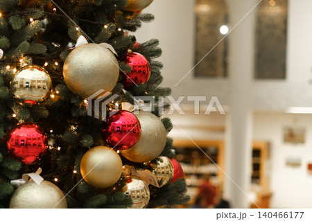 A Christmas tree stands tall with red and gold ornaments, bright lights, and a lively atmosphere in a festive location during the holidays. A Christmas tree stands tall with red and gold ornaments, bright lights, and a lively atmosphere in a festive location during the holidays. 140466177