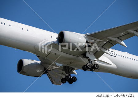 Modern commercial aircraft landing at international airport against blue sky showcases powerful jet engines and aerodynamic design during peak summer travel season. Landing gear and wing mechanics. Modern commercial aircraft landing at international airport against blue sky showcases powerful jet engines and aerodynamic design during peak summer travel season. Landing gear and wing mechanics. 140467223