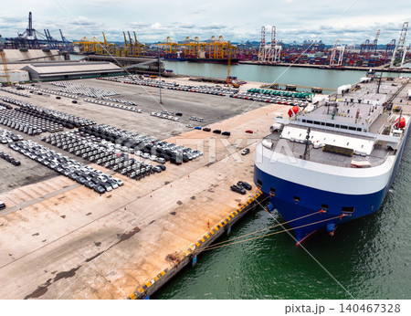 Logistics and transportation of new cars at terminal port for export. Container truck and crane bridge in shipyard. Import export and transport industry. Terminal port for export transport by ship. Logistics and transportation of new cars at terminal port for export. Container truck and crane bridge in shipyard. Import export and transport industry. Terminal port for export transport by ship. 140467328