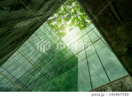 Eco-friendly building in modern city. Sustainable glass office structure with integrated greenery to reduce heat and carbon dioxide. Corporate architecture. Reducing CO2 emissions. Green environment. 140467589