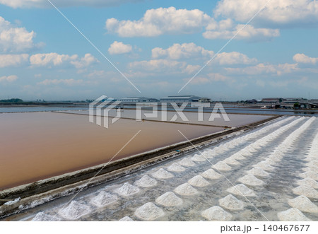 Aerial view of sea salt farm. Pile of brine salt. Raw material of salt industrial. Sodium Chloride mineral. Evaporation and crystallization of sea water. White salt harvesting. Agriculture industry. Aerial view of sea salt farm. Pile of brine salt. Raw material of salt industrial. Sodium Chloride mineral. Evaporation and crystallization of sea water. White salt harvesting. Agriculture industry. 140467677
