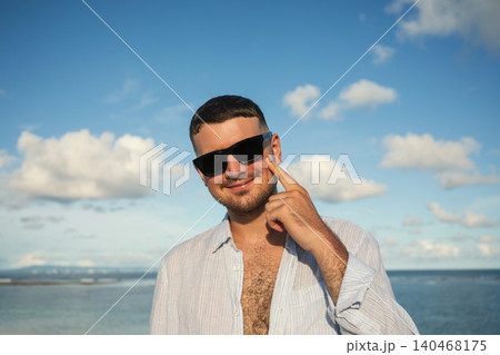 Man smiles and poses against bright sky at the beach 140468175