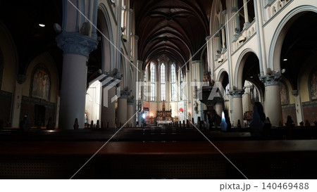 Inside a grand Catholic church with dark wooden pews 140469488