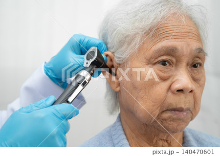 Otolaryngologist or ENT physician doctor examining senior patient ear with otoscope, hearing loss problem. Otolaryngologist or ENT physician doctor examining senior patient ear with otoscope, hearing loss problem. 140470601