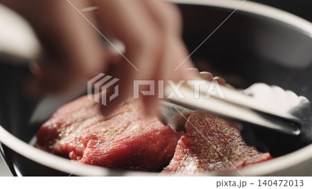 Close-up of raw steak fillet in black frying pan under soft directional light Close-up of raw steak fillet in black frying pan under soft directional light 140472013