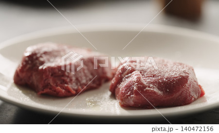 Two raw beef fillets on a white ceramic plate close-up Two raw beef fillets on a white ceramic plate close-up 140472156