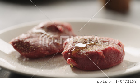 Close-up of two seasoned raw beef fillets on white plate 140472158