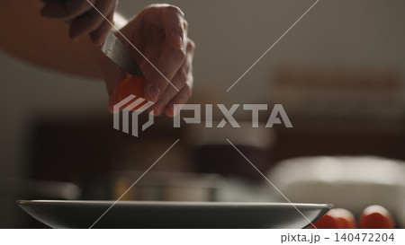 Hands plating penne pasta with cherry tomatoes on a ceramic bowl 140472204