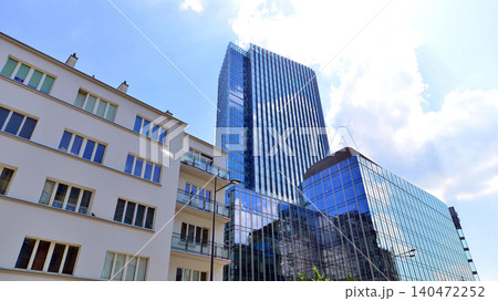 View of an modern apartment building standing next to a new modern office building with a glass facade. 140472252