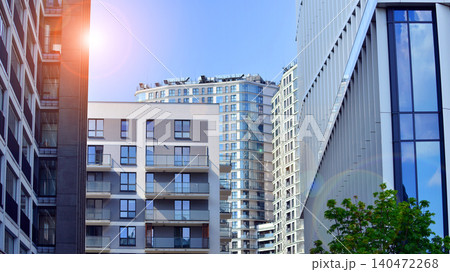 View of an modern apartment building standing next to a new modern office building with a glass facade. 140472268