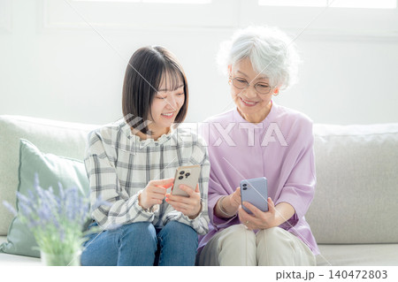 スマホを見るシニア女性と孫 140472803