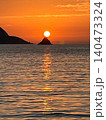 夕陽が立神の頂に重なる海景（奄美大島） 140473324