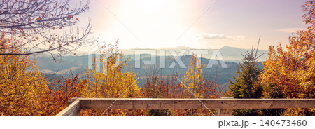 Autumn in the mountains. Panoramic view of the mountains and the valley in autumn from the wooden balcony. Carpathian Mountains. Bukovel, Ukraine. Real photo. Not AI Autumn in the mountains. Panoramic view of the mountains and the valley in autumn from the wooden balcony. Carpathian Mountains. Bukovel, Ukraine. Real photo. Not AI 140473460