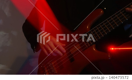 Musician playing red bass guitar on stage with red lighting 140473572