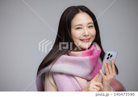 マフラーを巻き、携帯電話を使う若い女性 マフラーを巻き、携帯電話を使う若い女性 140473590