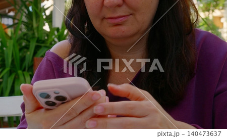 Woman holding smartphone outdoors in garden setting Woman holding smartphone outdoors in garden setting 140473637
