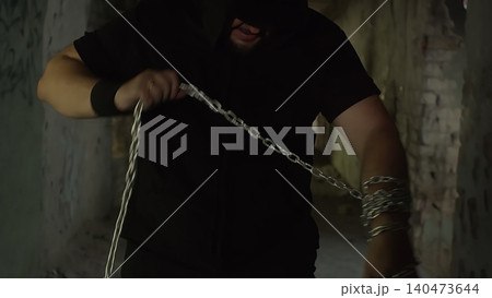 Man holding heavy metal chain in dark urban setting 140473644