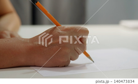 Child hand holding pencil writing on white paper Child hand holding pencil writing on white paper 140473834