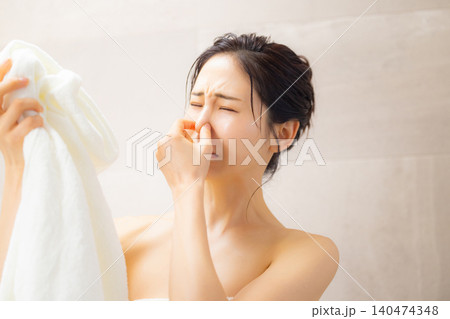 洗面所でタオルの匂いを嗅ぐ女性 洗面所でタオルの匂いを嗅ぐ女性 140474348