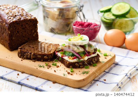 smorrebrod with rye toast bread and herring, boiling egg, red onions on wooden table, selective focus. smorrebrod with rye toast bread and herring, boiling egg, red onions on wooden table, selective focus. 140474412