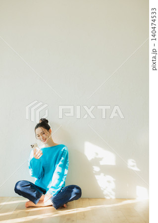 床に座ってスマホを見る若い女性　　 140474533