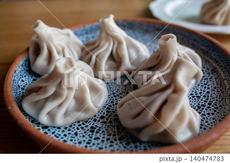 Savory dumplings arranged on a decorative plate showcase the culinary art of steaming in a friendly dining atmosphere at midday. Savory dumplings arranged on a decorative plate showcase the culinary art of steaming in a friendly dining atmosphere at midday. 140474783