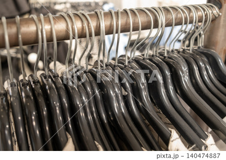 Hangers are neatly arranged on a metal rack within a bustling retail clothing store, showcasing the days vibrant shopping atmosphere. Hangers are neatly arranged on a metal rack within a bustling retail clothing store, showcasing the days vibrant shopping atmosphere. 140474887