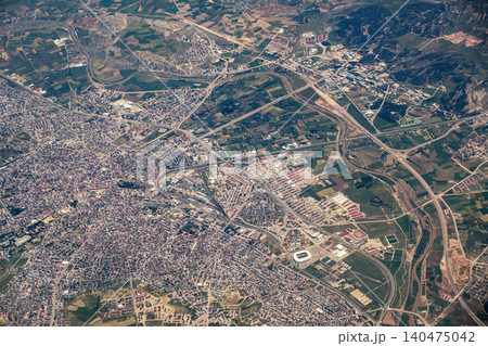 Birds-eye view captures the contrast between the citys dense structures and the surrounding agricultural fields, highlighting transportation routes. 140475042