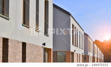 Terraced family homes in newly developed housing estate. The real estate market in the suburbs. New single family houses in a new development area. Residential homes with modern facade.  140475331
