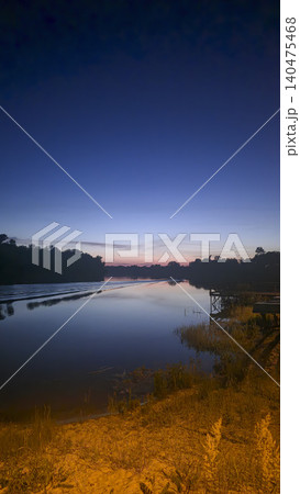 A picturesque sunset over the river with reflections of clouds and silhouettes of trees A picturesque sunset over the river with reflections of clouds and silhouettes of trees 140475468