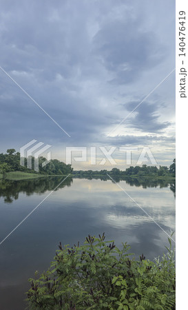 A deep river surrounded by trees and plants Thickets of reeds. Voluminous clouds A deep river surrounded by trees and plants Thickets of reeds. Voluminous clouds 140476419