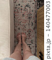Close Up Bare Legs and Feet on Vintage Persian Rug in Living Room 140477003