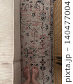 Bare Feet Standing on Vintage Persian Rug Between Sofa and Wooden Cabinet 140477004