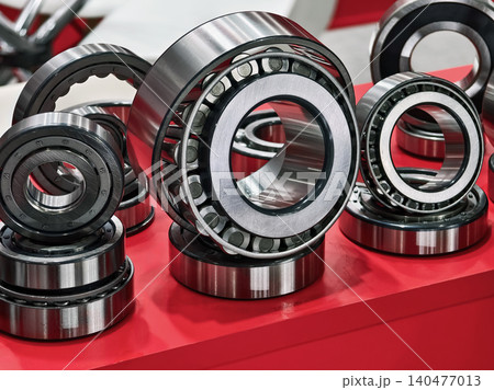 Various types of ball bearings arranged on a red display table at a mechanical exhibition in an industrial setting Various types of ball bearings arranged on a red display table at a mechanical exhibition in an industrial setting 140477013