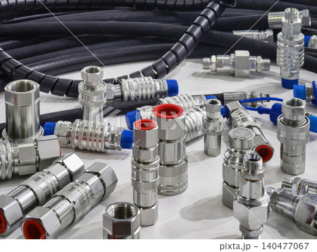 Variety of metal fittings and hoses used in mechanical systems on a table in a workshop setting during daylight hours Variety of metal fittings and hoses used in mechanical systems on a table in a workshop setting during daylight hours 140477067