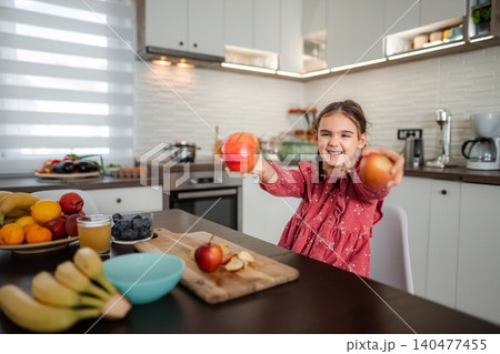 Child smiling offering healthy fresh apples in kitchen Child smiling offering healthy fresh apples in kitchen 140477455