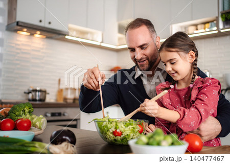 Father and daughter preparing healthy meal together in kitchen Father and daughter preparing healthy meal together in kitchen 140477467