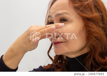 Mature Asian woman pinching her nose due to unpleasant smell. Senior lady with facial expression of disgust blocking her nose. Concept of bad odor, hygiene, allergy or healthcare issue. Mature Asian woman pinching her nose due to unpleasant smell. Senior lady with facial expression of disgust blocking her nose. Concept of bad odor, hygiene, allergy or healthcare issue. 140477691