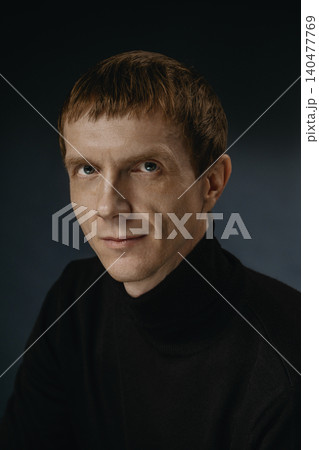 Portrait of a person with short hair and a black sweater looking at the camera indoors Portrait of a person with short hair and a black sweater looking at the camera indoors 140477769