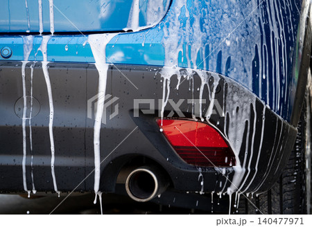 Blue car wash with white soap foam and professional auto care service. Car cleaning service concept. Vehicle cleaning service. Foam wash car detailing. Blue luxury SUV car is covered with white foam. Blue car wash with white soap foam and professional auto care service. Car cleaning service concept. Vehicle cleaning service. Foam wash car detailing. Blue luxury SUV car is covered with white foam. 140477971