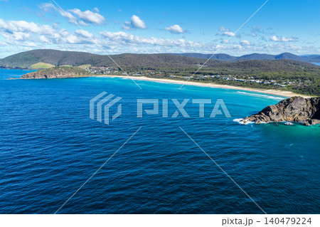 Aerial scene capturing Boomerang Beach near Pacific Palms, NSW, Australia, nestled between rugged rocky headlands. The sweeping sandy shoreline, clear ocean waters and dramatic coastal landscape 140479224