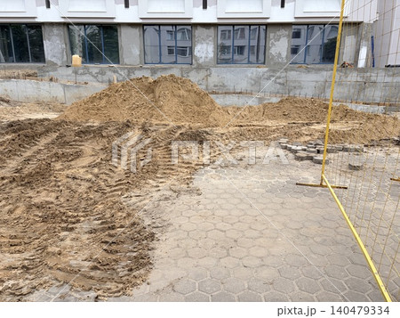 an active construction or landscaping site situated next to a modern building. an active construction or landscaping site situated next to a modern building. 140479334